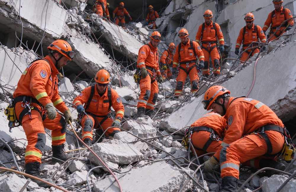 Wide-angle view of collapse rescue scene with rescue team in technical orange with yellow reflective trim rescue clothing for emergency rescue operations and rescue clothing bulk procurement planning