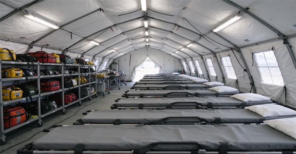 Wide interior view of white medical emergency tent with folding cots and medical supplies showing field hospital shelter