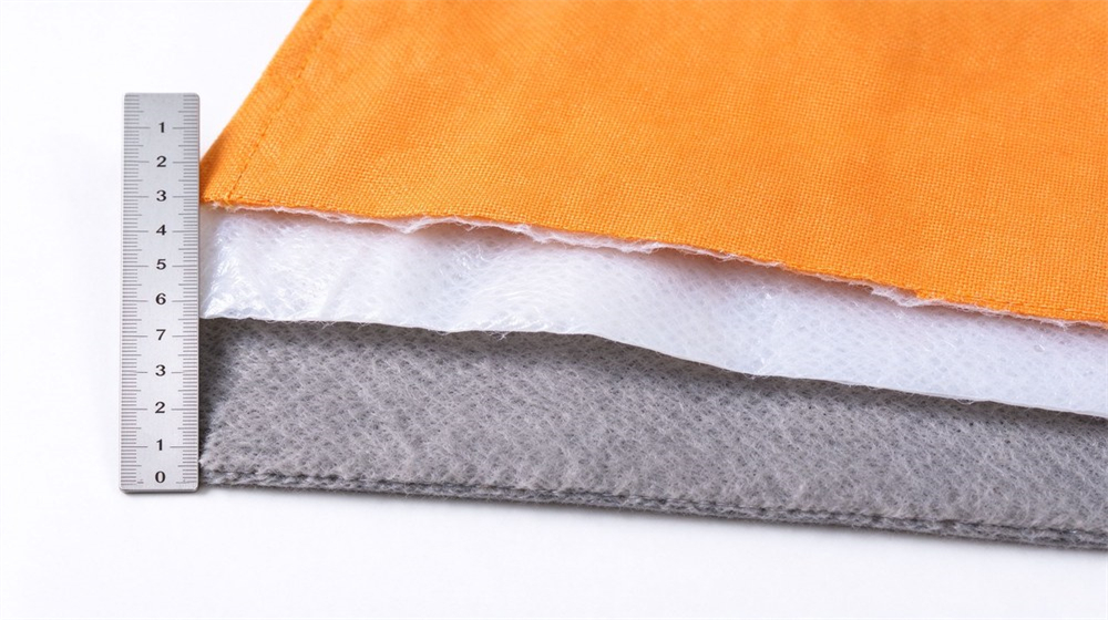 Close up studio shot showing three layer structure of firefighter turnout gear: Nomex outer shell, moisture barrier and thermal liner, layered fabric samples on light gray background Close up studio shot showing three layer structure of firefighter turnout gear: Nomex outer shell, moisture barrier and thermal liner, layered fabric samples on light gray background