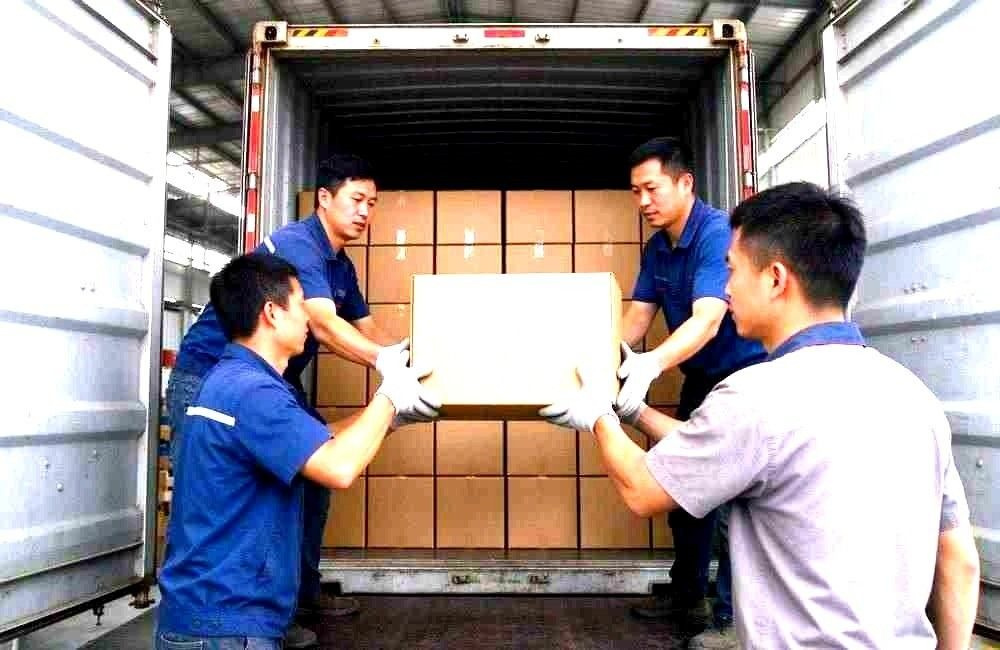 Workers loading blanket cartons into a shipping container for camp relief delivery to African ports, showing bulk relief supplies export logistics