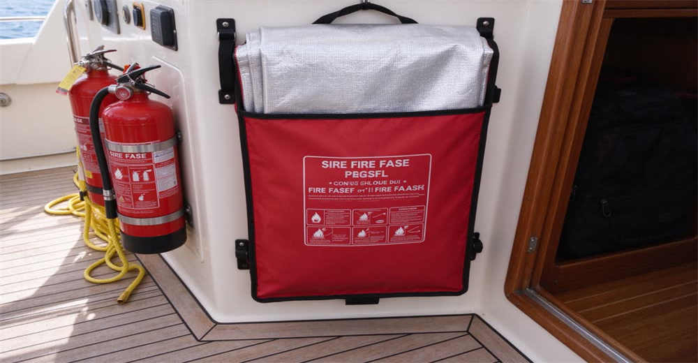 Front view of grey fire blanket mounted on galley wall showing marine fire safety equipment for boat kitchen Front view of grey fire blanket mounted on galley wall showing marine fire safety equipment for boat kitchen